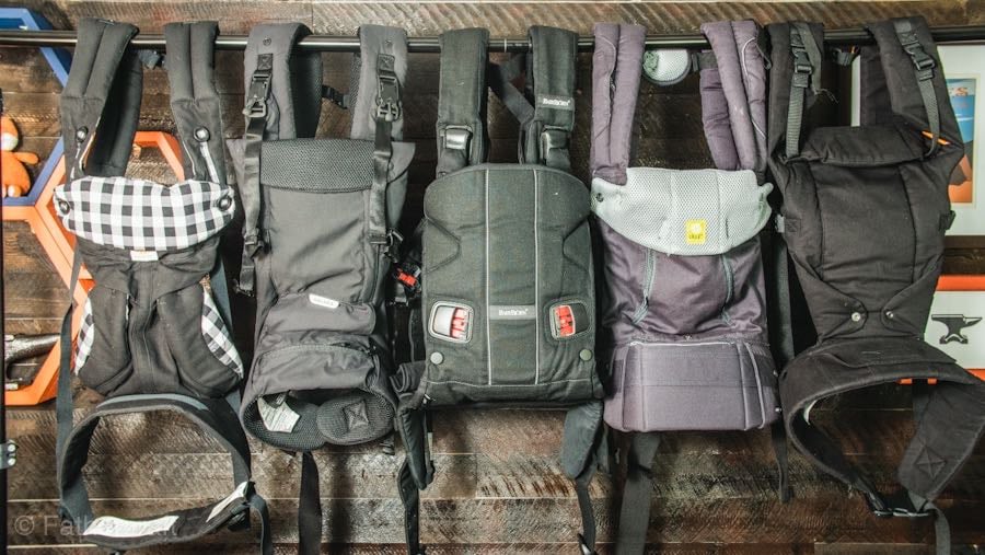 Baby carriers arrange on a wooden wall