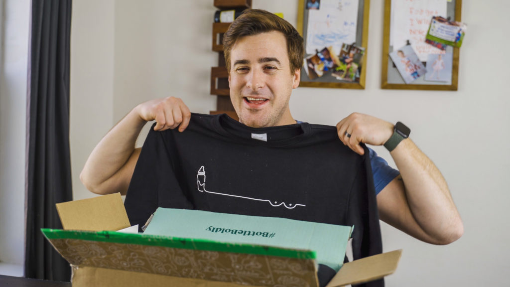 A guy holding up a Bobbie baby formula sweatshirt