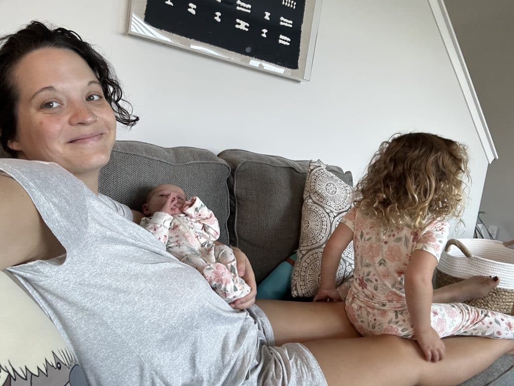 Me, lounging on the couch. I'm holding my newborn and my three-year-old sits on my lap, facing away from me.