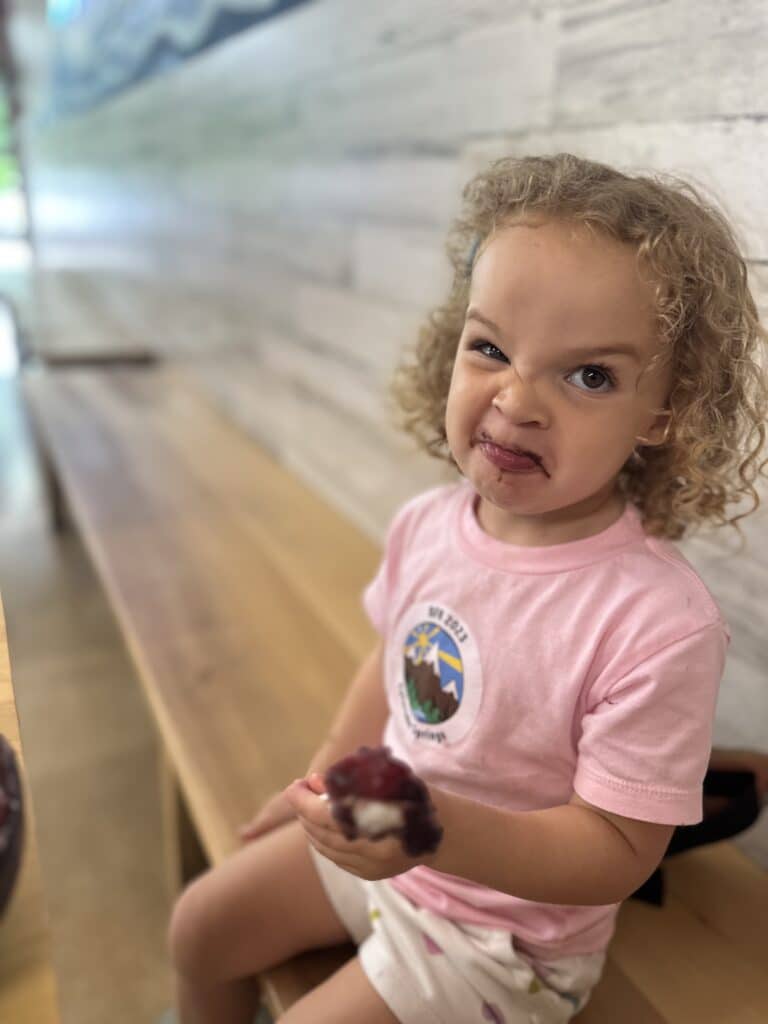 An image of a toddler making a silly face during lunch