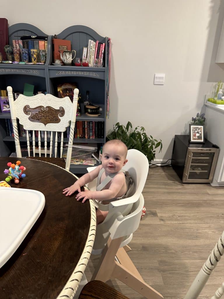 The Mockingbird high chair is shown pushed up to the table with the baby in it