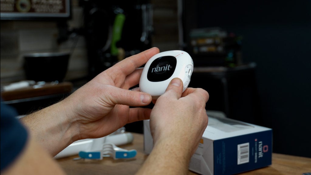 Hands holding the Nanit Pro camera in front of the box