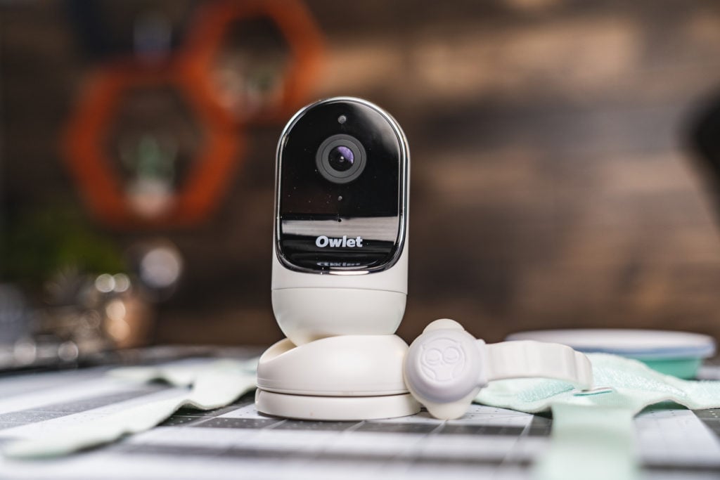 An Owlet Cam on a table with other Owlet Smart Sock gear