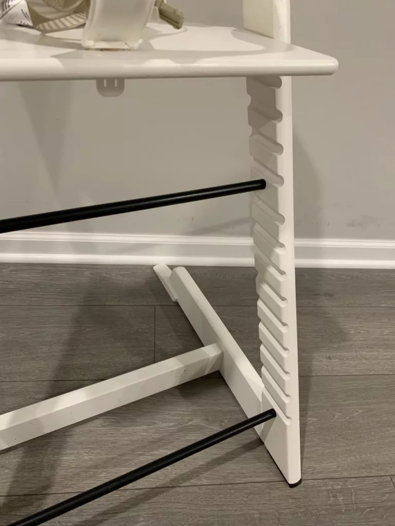 A close-up image of a white Stokke Tripp Trapp, showing 13 different footplate placement options